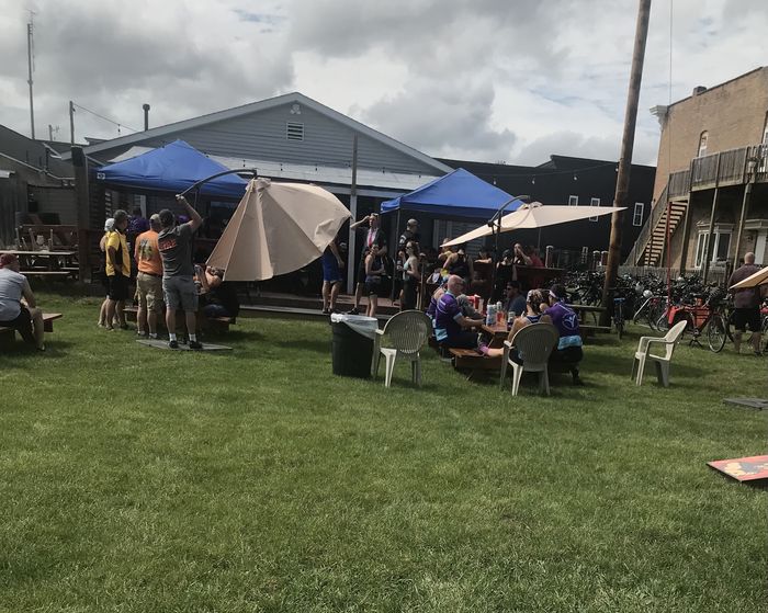 A crowd on the back lawn under umbrellas and tents